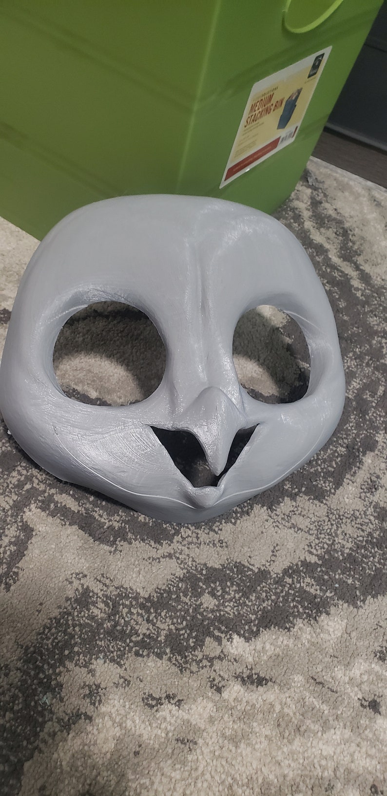 May include: A gray, unpainted, animal mask with large eye holes and a small mouth opening. The mask is made of a smooth, hard material.
