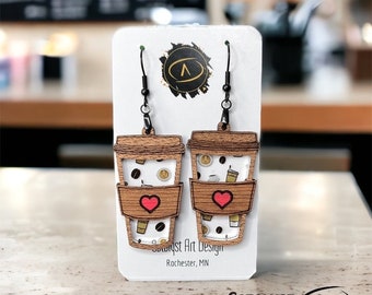 May include: A pair of wooden coffee cup earrings with a red heart on each cup. The earrings are on a white card with the text "Catalyst Art Design, Rochester, MN".