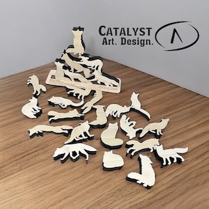 May include: A set of wooden fox stacking toys. The pieces are black and natural wood and feature different fox silhouettes. The packaging includes the text "Stacking Foxes".