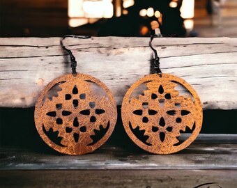 May include: A pair of brown leather earrings with a cut-out design. The earrings are round and have a rustic, distressed look.
