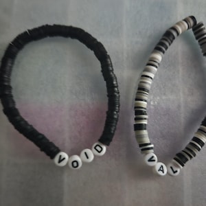 May include: Two black and white beaded bracelets with the words "VOID" and "VAL" spelled out in white beads.