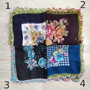May include: Four square scarves with floral patterns and crocheted borders. The scarves are in shades of blue, black, and brown. The borders are in shades of green, white, and pink.