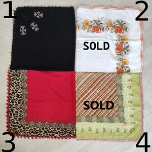 May include: Four square scarves with different patterns and colors. The top left scarf is black with a white design. The top right scarf is white with a floral design and the text "SOLD". The bottom left scarf is red with a leopard print border. The bottom right scarf is green with a striped pattern and the text "SOLD".