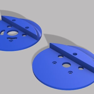 May include: Two blue, circular objects with a flat, angled top section. Each disc has several holes of varying sizes. The objects are rendered in a 3D style, with shadows suggesting depth and dimension. The design is simple and geometric.