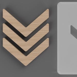 May include: Three wooden chevron-shaped wall decor pieces arranged in a downward-pointing direction. The wood has a light, natural finish. The background is a solid gray color, with a white, rectangular shape on the right side.