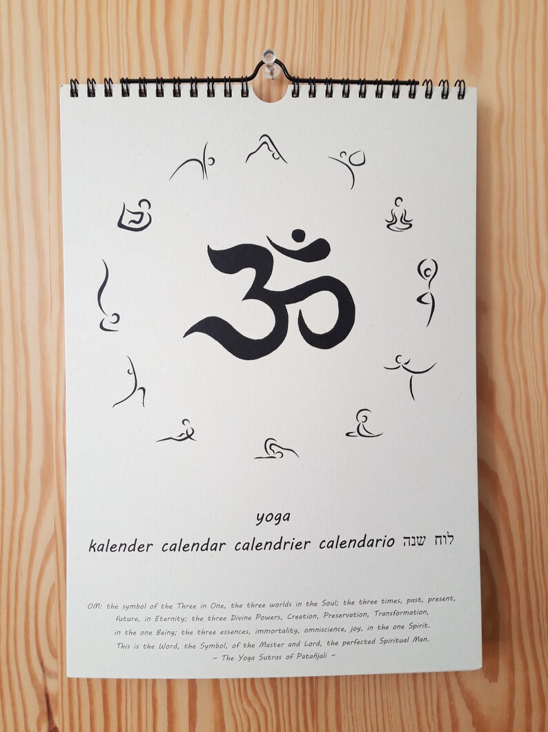 May include: A white calendar with a black Om symbol in the center. The calendar is titled "yoga" and has the words "kalender, calendar, calendrier, calendario, לוח שנה" written below the title.