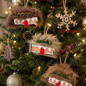May include: Three fuzzy monster ornaments hanging on a tree. Each features long faux fur in dark brown, mixed brown, or light brown, four green eyes, white felt teeth, and a red felt tongue. Text labels read Dark brown#1, Mixed brown#2, and Light brown#3.