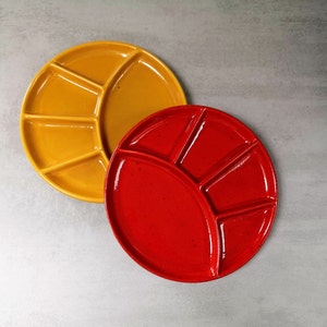 Può includere: Due piatti divisi in ceramica, uno giallo e uno rosso, con sezioni per intingere salse o condimenti.