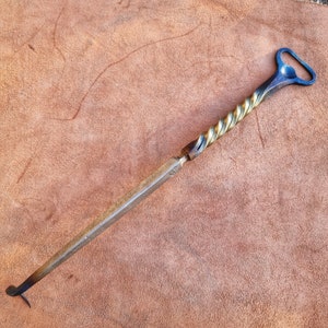 Könnte beinhalten: Ein verdrehter Flaschenöffner aus Metall mit goldener und blauer Oberfläche. Der Öffner hat eine Schlaufe oben zum Aufhängen.
