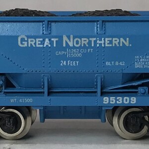 May include: A blue model train car with the words "Great Northern" printed on the side. The car is filled with a dark substance and has the number 95309 printed on it. The car is approximately 24 feet long.