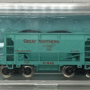 May include: A teal model train car with the words "Great Northern" printed on the side. The model train car is in a clear plastic case. The model train car has black wheels and is labeled "81646".