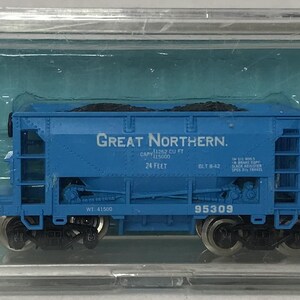 May include: A blue model train car from the Great Northern railway, encased in a clear plastic box. The car has black wheels and the text "Great Northern" printed on the side. The model is a detailed replica of a freight car.