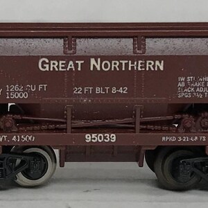 May include: A brown model train car with the words "Great Northern" in white. The car has black wheels and the text "CAPY 1262 CU FT 15000" and "22 FT BLT 8-42". The model is a miniature replica of a freight car.