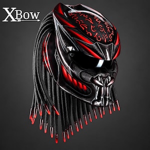 May include: A black and red motorcycle helmet featuring a stylized faceplate with a dark visor and a series of long, black, braided cords hanging from the back, each tipped with a translucent red point. The text XBow is visible in the top left corner.