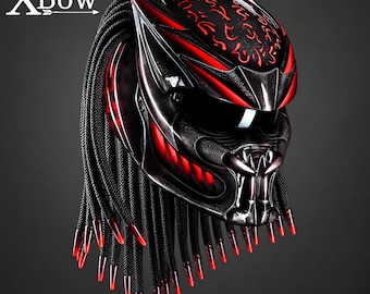 May include: A black and red motorcycle helmet featuring a stylized faceplate with a dark visor and a series of long, black, braided cords hanging from the back, each tipped with a translucent red point. The text XBow is visible in the top left corner.