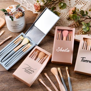 Può includere: Set di tre set di pennelli per il trucco personalizzati in custodie rosa e blu. Le custodie hanno uno specchio e sono etichettate con i nomi "Sheila", "Tamra" e "Jessica Bridesmaid 2023.08.24".
