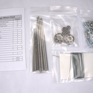 May include: A list of parts and their quantities for a large moon clock kit. The parts are organized in a table with the description and count of each part. The parts are packaged in small plastic bags.
