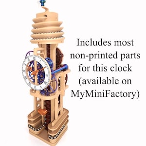 May include: A vertical mechanical marble clock with a beige frame, blue and brown internal gears, and a white clock face featuring black Roman numerals. The text reads: Includes most non-printed parts for this clock (available on MyMiniFactory).