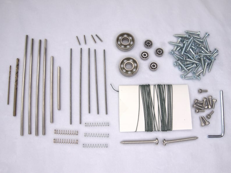 May include: Assortment of metal hardware including screws, springs, rods, and bearings.  The hardware is arranged on a white surface.