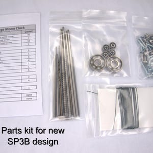 May include: A parts kit for a large moon clock, with a list of parts and their quantities. The kit includes screws, dowel pins, a spring, bearings, fishing line, and other small parts. The parts are organized in small plastic bags.