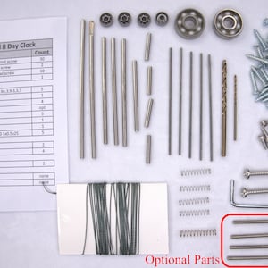 K&ouml;nnte beinhalten: Eine Nahaufnahme eines Bausatzes f&uuml;r eine kleine 8-Tage-Uhr. Der Bausatz enth&auml;lt verschiedene Metallst&auml;be, Schrauben, Federn, Lager und einen Bohrer. Der Bausatz enth&auml;lt auch ein St&uuml;ck Angelschnur und eine kleine Spule Draht. Der Bausatz ist auf einer wei&szlig;en Oberfl&auml;che mit einer Liste der Teile und ihrer Mengen ausgelegt.