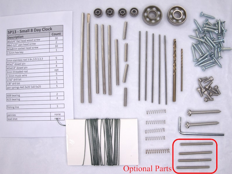 K&ouml;nnte beinhalten: Eine Nahaufnahme eines Bausatzes f&uuml;r eine kleine 8-Tage-Uhr. Der Bausatz enth&auml;lt verschiedene Metallst&auml;be, Schrauben, Federn, Lager und einen Bohrer. Der Bausatz enth&auml;lt auch ein St&uuml;ck Angelschnur und eine kleine Spule Draht. Der Bausatz ist auf einer wei&szlig;en Oberfl&auml;che mit einer Liste der Teile und ihrer Mengen ausgelegt.