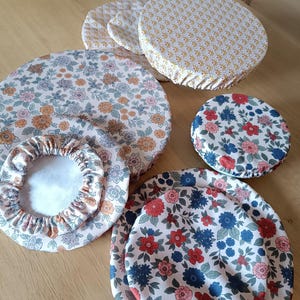 Puede incluir: Un conjunto de cubiertas reutilizables para cuencos de varios tama&ntilde;os y con estampados florales. Las cubiertas presentan una mezcla de colores, incluyendo rosa, naranja, azul y rojo, con bordes el&aacute;sticos para un ajuste seguro. La tela tiene una est&eacute;tica vintage.