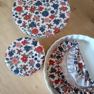 Puede incluir: Tres cubiertas de tela floral en rojo, azul y rosa. Las cubiertas son circulares y se ajustan a los cuencos. Una cubierta est&aacute; sobre una fuente para pastel blanca. El estampado floral est&aacute; sobre un fondo blanco.