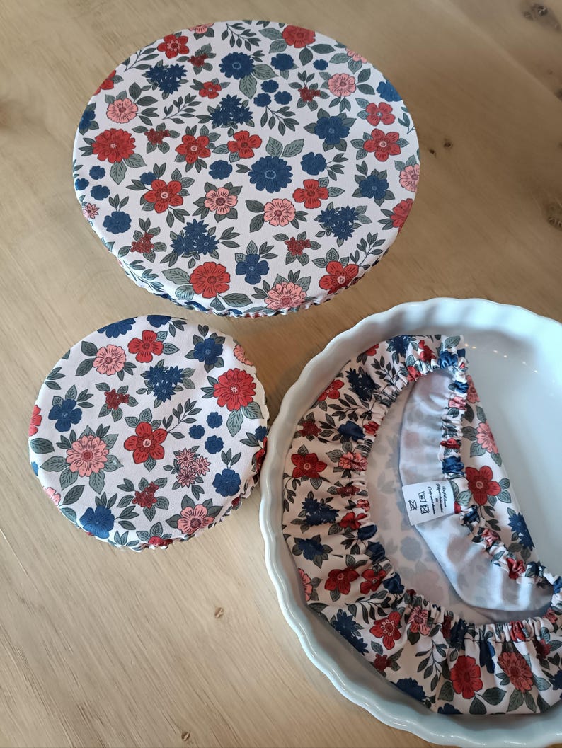 Puede incluir: Tres cubiertas de tela floral en rojo, azul y rosa. Las cubiertas son circulares y se ajustan a los cuencos. Una cubierta est&aacute; sobre una fuente para pastel blanca. El estampado floral est&aacute; sobre un fondo blanco.