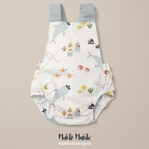 May include: White baby romper with a whimsical ocean-themed pattern featuring whales, fish, crabs, and jellyfish. The romper has light blue straps and is decorated with the text "Marta Munte Pattern Design Studio".