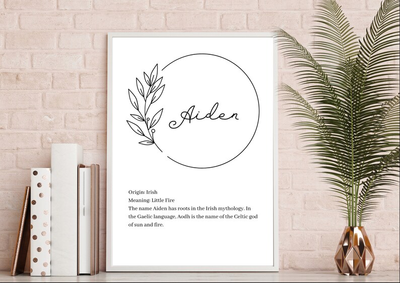 May include: A white framed wall art print featuring the name Aiden in black script inside a circular line drawing with a leafy branch. Below the name, black text reads: Origin: Irish, Meaning: Little Fire, The name Aiden has roots in the Irish mythology. In the Gaelic language, Aodh is the name of the Celtic god of sun and fire.