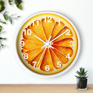 May include: White round clock with black numbers and hands. The clock face features a graphic of a sliced orange with a white background.