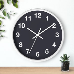 May include: A white framed clock with a black face and white numbers. The clock hands are white and the time is set to 10:10.