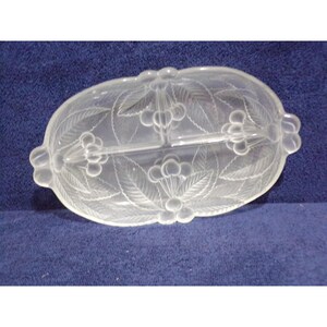 May include: An oval clear glass divided serving dish featuring a frosted relief pattern of cherries and leaves. The dish has two distinct sections separated by a central glass divider and includes small decorative handles on each side.