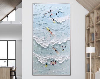 May include: A painting of a blue ocean with white waves and people swimming and surfing. The painting is in a modern living room with a white couch and a wooden coffee table.