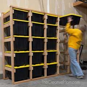 May include: A wooden storage shelf unit with multiple black bins with yellow lids. The unit is in a garage setting. TheCreativeMom.com is printed on the bottom of the image.