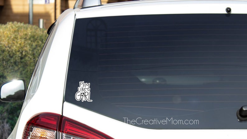 May include: White car with a black window sticker that says "Play Like a Girl" on the back window.