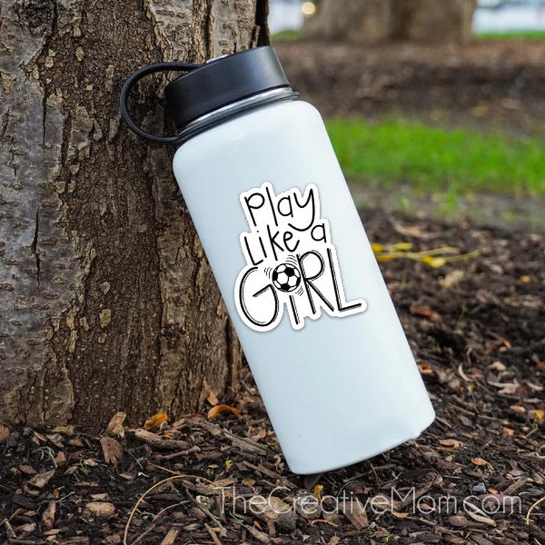 May include: White water bottle with a black sticker that says "Play like a girl" with a soccer ball graphic.