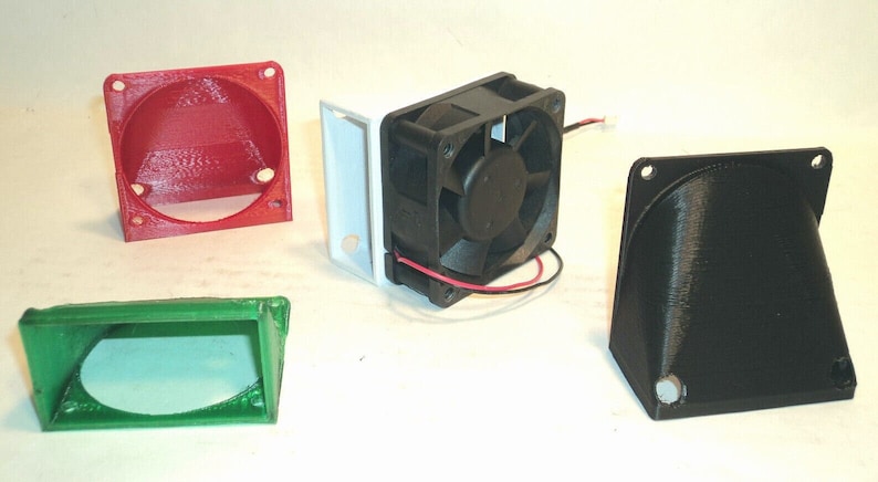 May include: An assortment of 3D-printed electronic components, including a red and green housing, a black fan, and a black housing. The components are designed for electronics projects and DIY builds.