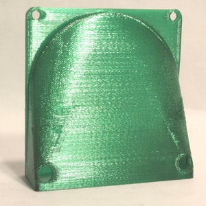 May include: A green plastic 3D printed fan shroud with two holes on the top and two holes on the bottom.