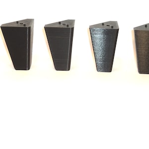 Puede incluir: Ocho patas de muebles triangulares negras con un acabado liso. Las patas miden aproximadamente 10 cm de alto y tienen una base de 7,5 cm.