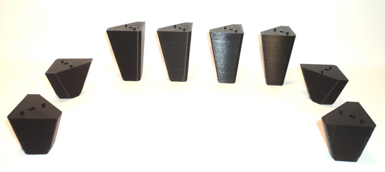 Puede incluir: Ocho patas de muebles triangulares negras con un acabado liso. Las patas miden aproximadamente 10 cm de alto y tienen una base de 7,5 cm.