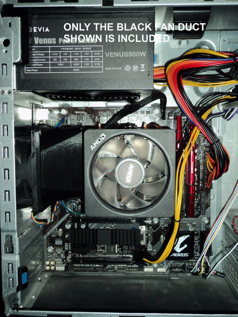 May include: A close-up view of the inside of a computer case. The motherboard is visible, along with a black fan duct, a power supply unit, and various cables. The power supply unit is labeled "VENUS500W" and has a label with specifications. The motherboard has an AMD logo and an AORUS logo.