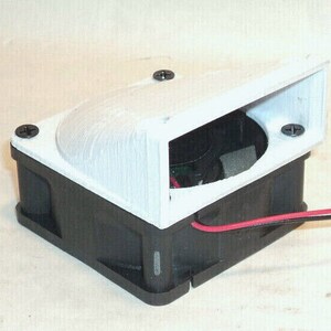 May include: A black and white electronic fan with a white, angled shroud. The shroud is secured with black screws. Red and black wires extend from the fan.