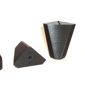 Puede incluir: Cuatro patas de muebles triangulares negras con un agujero para tornillo en la parte inferior. Las patas est&aacute;n hechas de un material texturizado y tienen una forma ligeramente redondeada.