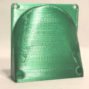May include: A green plastic 3D printed fan shroud with two holes on the top and two holes on the bottom.