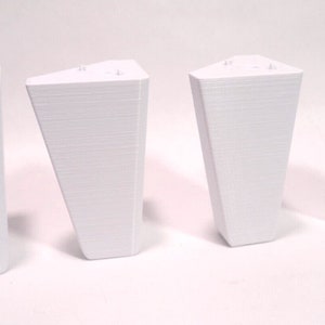 Puede incluir: Cuatro patas de muebles de pl&aacute;stico blanco. Cada pata tiene forma triangular y una superficie lisa ligeramente texturizada.