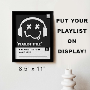 Peut inclure: Impression encadrée noire avec une illustration blanche d'un visage souriant portant un casque. Le texte "PLAYLIST TITLE" est sous l'illustration. Le texte "A PLAYLIST BY / FOR NAME HERE" est sous le titre. Le texte "PUT YOUR PLAYLIST ON DISPLAY!" est à droite de l'impression. L'impression mesure 8,5 pouces par 11 pouces.