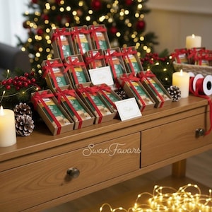 May include: A collection of rectangular gift boxes arranged in rows, each containing a green and white Starbucks coffee packet tied with a red ribbon. The boxes are displayed on a wooden table with small white cards and the text Swan Favars.