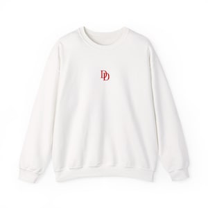 May include: A white crew neck sweatshirt with long sleeves. The sweatshirt features a small, red double-D logo centered on the chest. The garment is made of a soft, comfortable material.